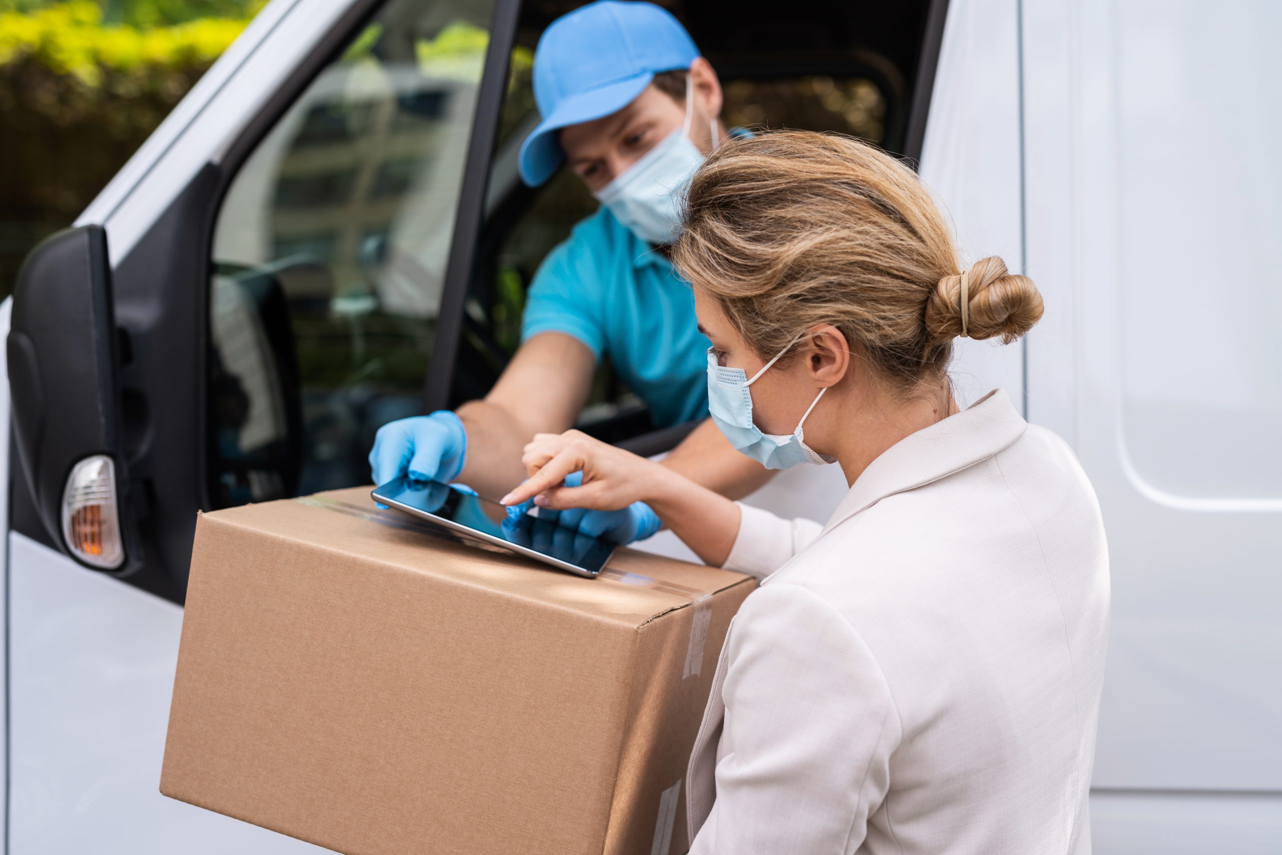Woman receiving package from the delivery man on a van